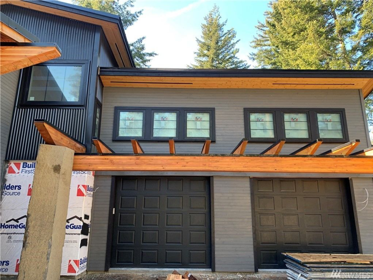 a two story house under construction in the woods.