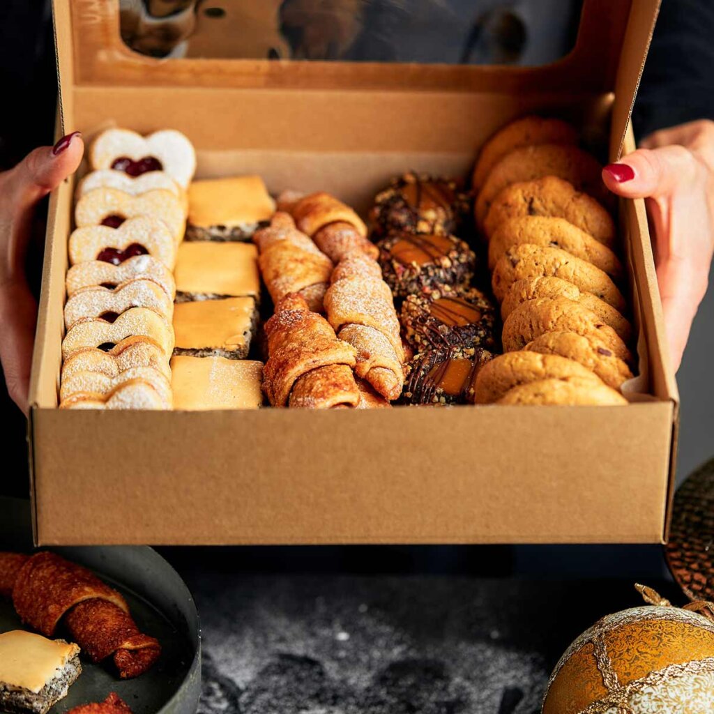 a woman holding a box full of pastries.