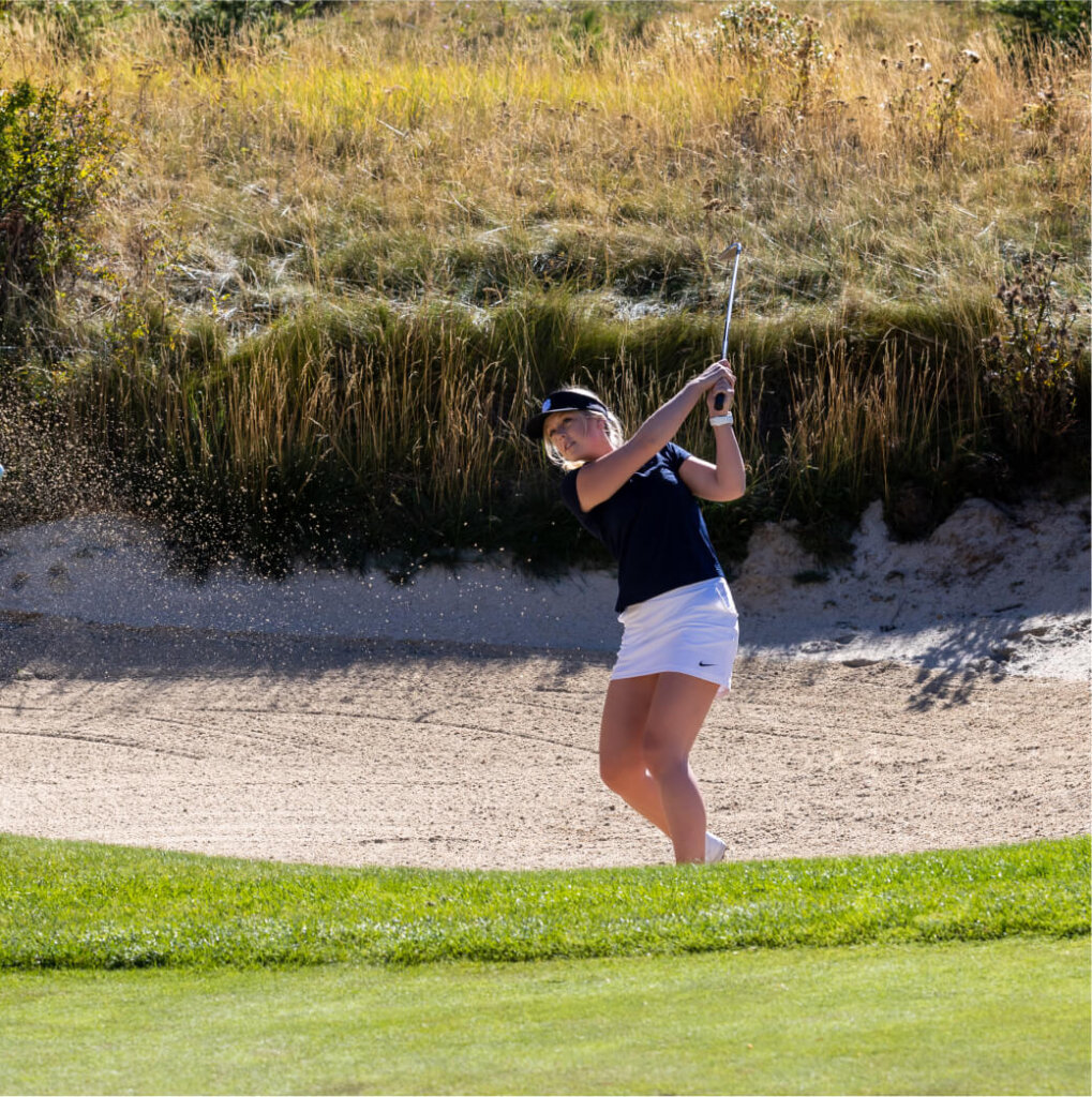 A golfer expertly hits a shot from a sand bunker under the bright skies at Suncadia Resort, with lush grass and vibrant vegetation framing the scene, just minutes away from delightful Cle Elum restaurants.