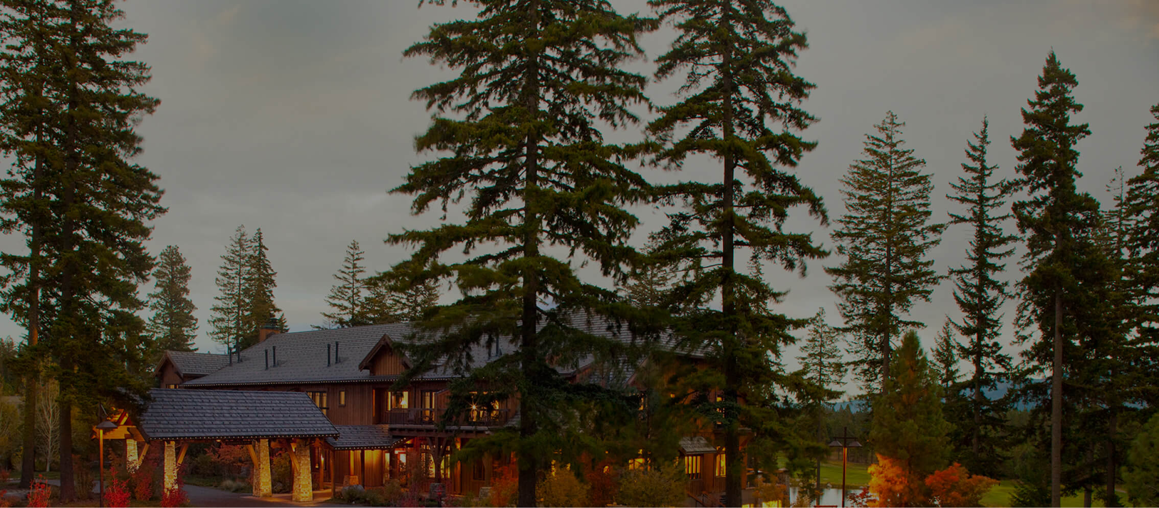 A large house nestled in a forested area with towering evergreen trees and overcast skies, reminiscent of the serene landscapes found in Suncadia.