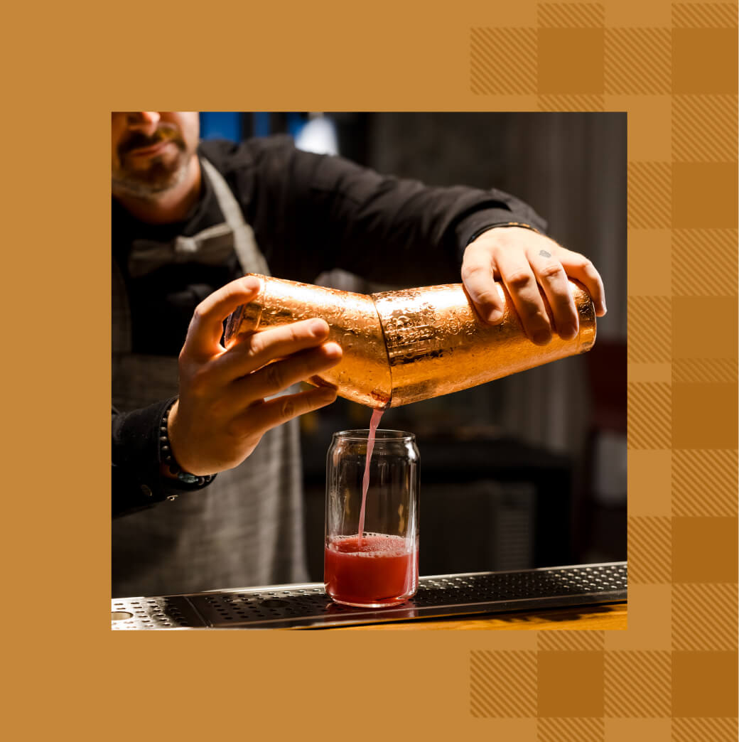 At a bar in Suncadia Resort, the bartender artfully pours a red cocktail from a copper shaker into a glass, blending flavors as seamlessly as the luxurious Suncadia real estate blends with the scenic landscape.