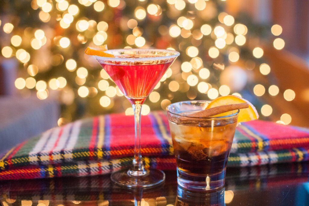 two cocktails on a table with a christmas tree in the background.