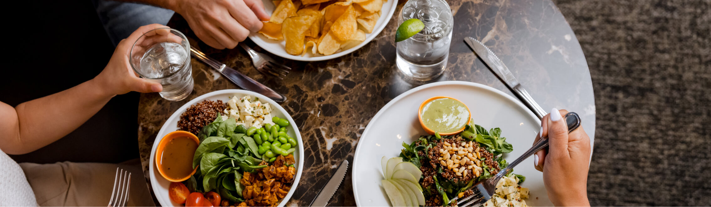 Two people dining at a Cle Elum restaurant enjoy salads, chips, and drinks on a marble table.