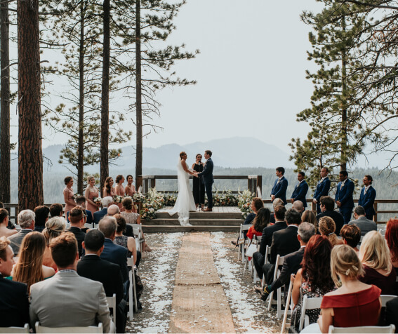 An outdoor wedding ceremony unfolds at the scenic Suncadia Resort, with a bride and groom at the altar surrounded by bridesmaids, groomsmen, and seated guests. The forested mountain backdrop adds to the enchanting ambiance of this Washington location.