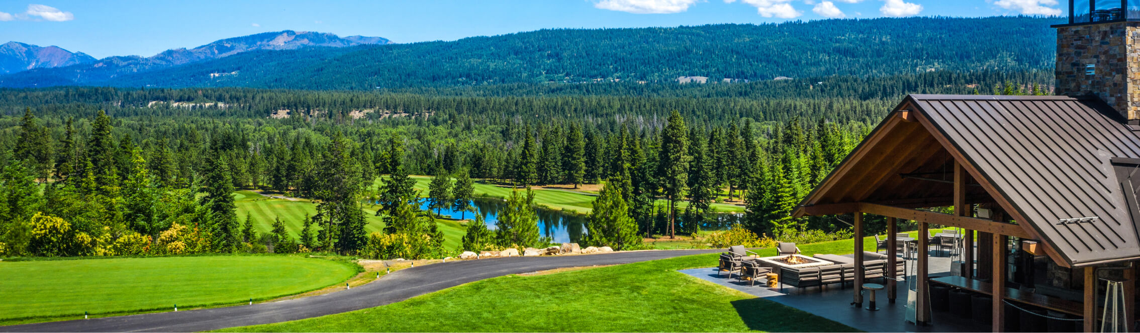 Scenic view of Suncadia's golf course surrounded by lush green trees and mountains in the background, with a charming wooden structure on the right. Nearby, Cle Elum restaurants offer delightful dining experiences to complete your visit.