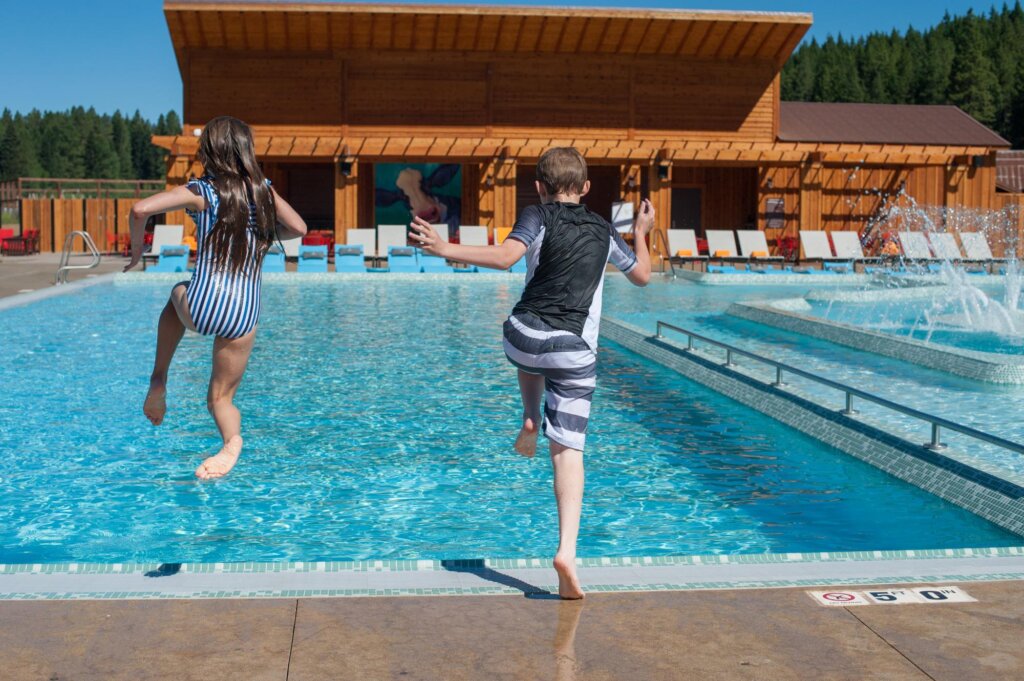 a couple of kids jumping into a swimming pool.