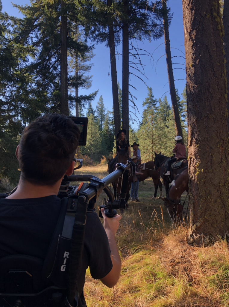 a group of people riding horses through a forest.