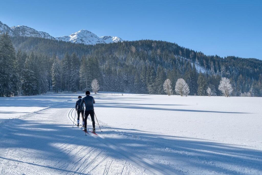 a couple of people riding skis across a snow covered field.