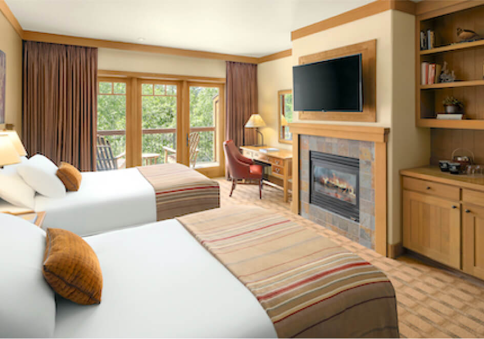 Enjoy a cozy stay in our hotel room at Suncadia, featuring two double beds, a fireplace, a wall-mounted TV, and a desk with a chair. Bask in natural light streaming through large windows with views of lush greenery. Explore nearby Cle Elum restaurants for delightful dining experiences.