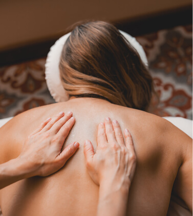 A person enjoys a back massage on a cozy table, surrounded by the peaceful ambiance of Suncadia Resort, with a beautifully patterned floor beneath enhancing the serene atmosphere.