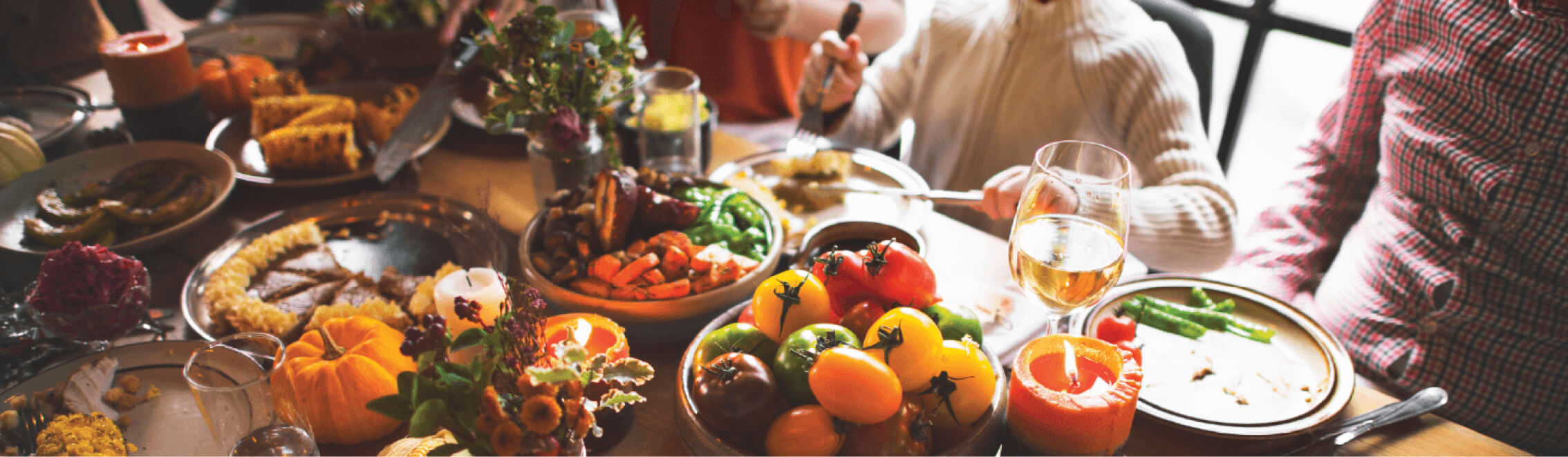 A festive table setting at Suncadia Resort in Washington features an array of dishes like roasted vegetables, peppers, and corn, beautifully complemented by candles and wine glasses. Guests are seated around the table, capturing the cozy dining experience reminiscent of Cle Elum restaurants.