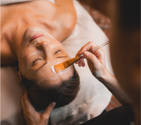 At Suncadia Resort in Washington, a person enjoys a luxurious facial treatment. A brush gently applies a cream mask to their forehead while another hand supports their head, offering tranquility and relaxation.