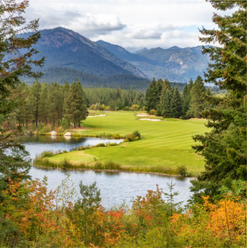 Nestled in the breathtaking landscape of Suncadia Resort, Washington, a golf course with a green fairway is surrounded by trees, a small lake, and distant mountains under a cloudy sky.