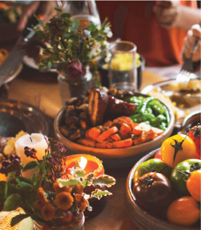 A table set with various dishes, including roasted vegetables and colorful tomatoes, captures the essence of dining at Suncadia Resort in Washington, surrounded by small floral arrangements.