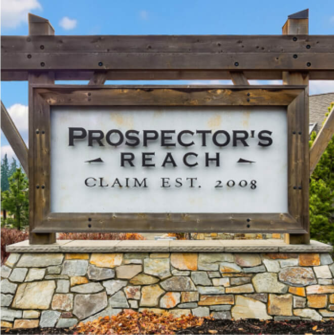 A wooden sign reads "Prospector's Reach, Claim Est. 2008," mounted on a stone base with trees and blue sky in the background, a welcoming sight for those exploring Suncadia real estate or enjoying nearby Cle Elum restaurants.