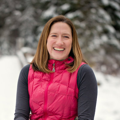 A person in a pink vest smiles outdoors with a snowy background, enjoying the serene beauty of Suncadia.