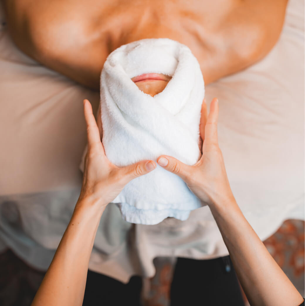 At the serene Suncadia Resort in Washington, a person enjoys a rejuvenating experience on a massage table, receiving a luxurious hot towel facial treatment. Surrounded by the tranquility of Suncadia homes and scenic real estate, relaxation is truly elevated.