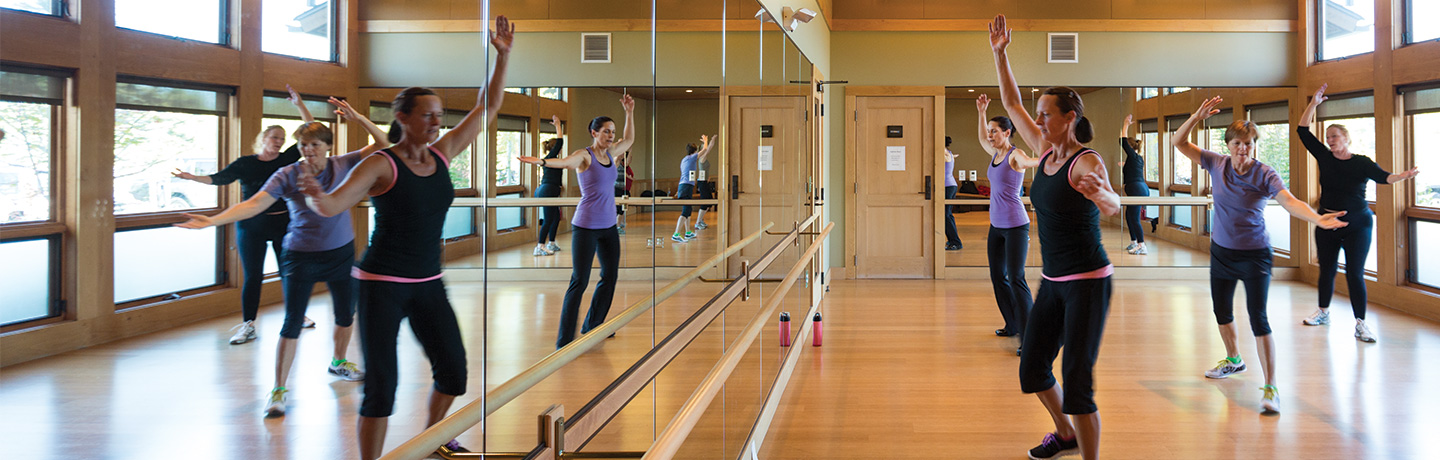 In a mirrored studio, people dance with raised arms, their movements as vibrant as the energy found at Suncadia Resort.