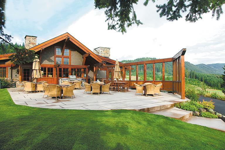 a large patio with chairs and tables in front of a house.