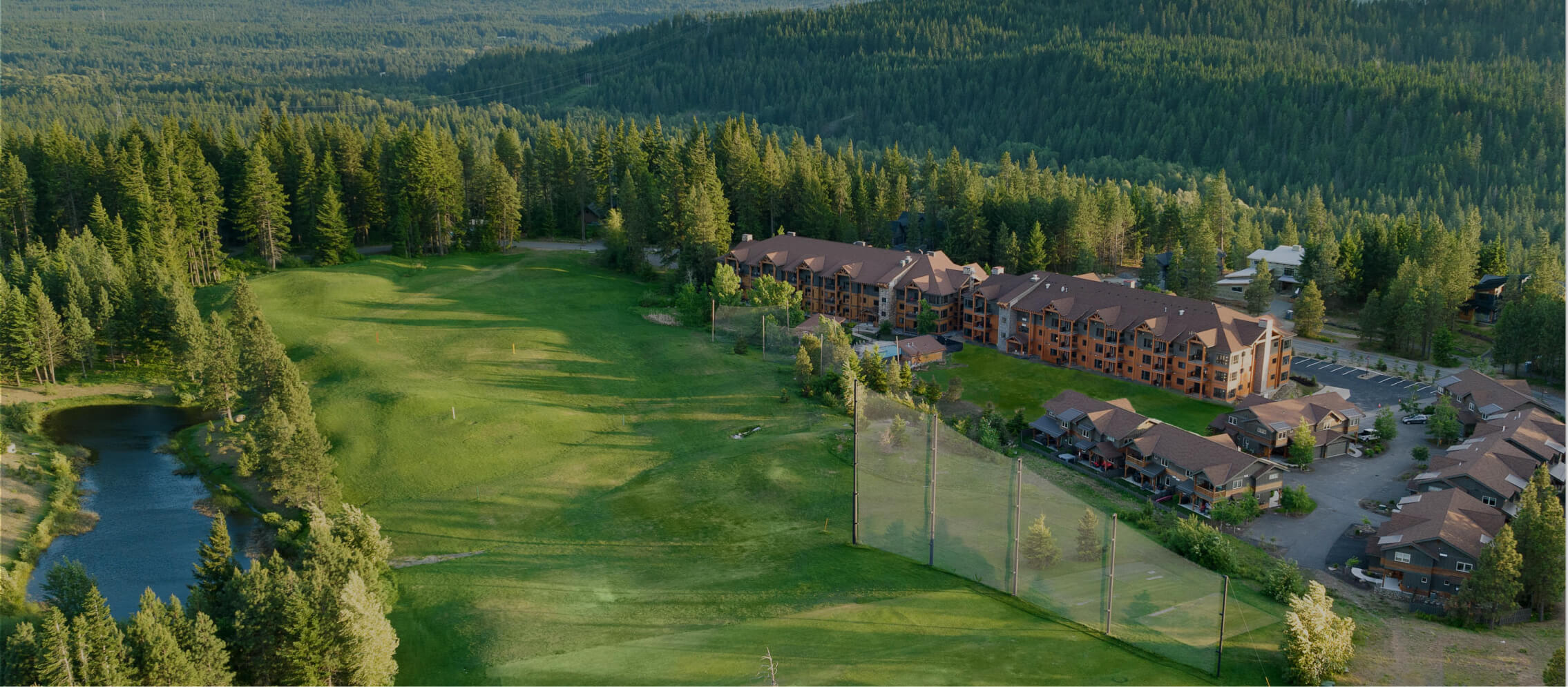 Aerial view of a large building complex nestled within dense forest, featuring Suncadia homes alongside a golf course and a small lake. Nearby Cle Elum restaurants offer delightful dining options in this serene setting.