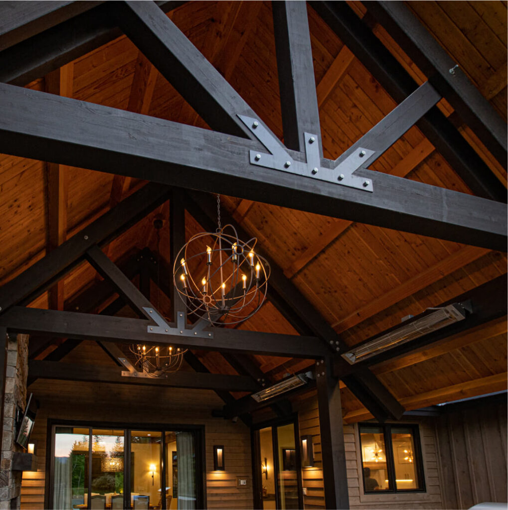 A room with a vaulted wooden ceiling featuring exposed beams, modern orb chandeliers, and large windows overlooks the lush landscapes of Suncadia. Perfectly blending rustic elegance with modern design, this inviting space captures the essence of Suncadia real estate.