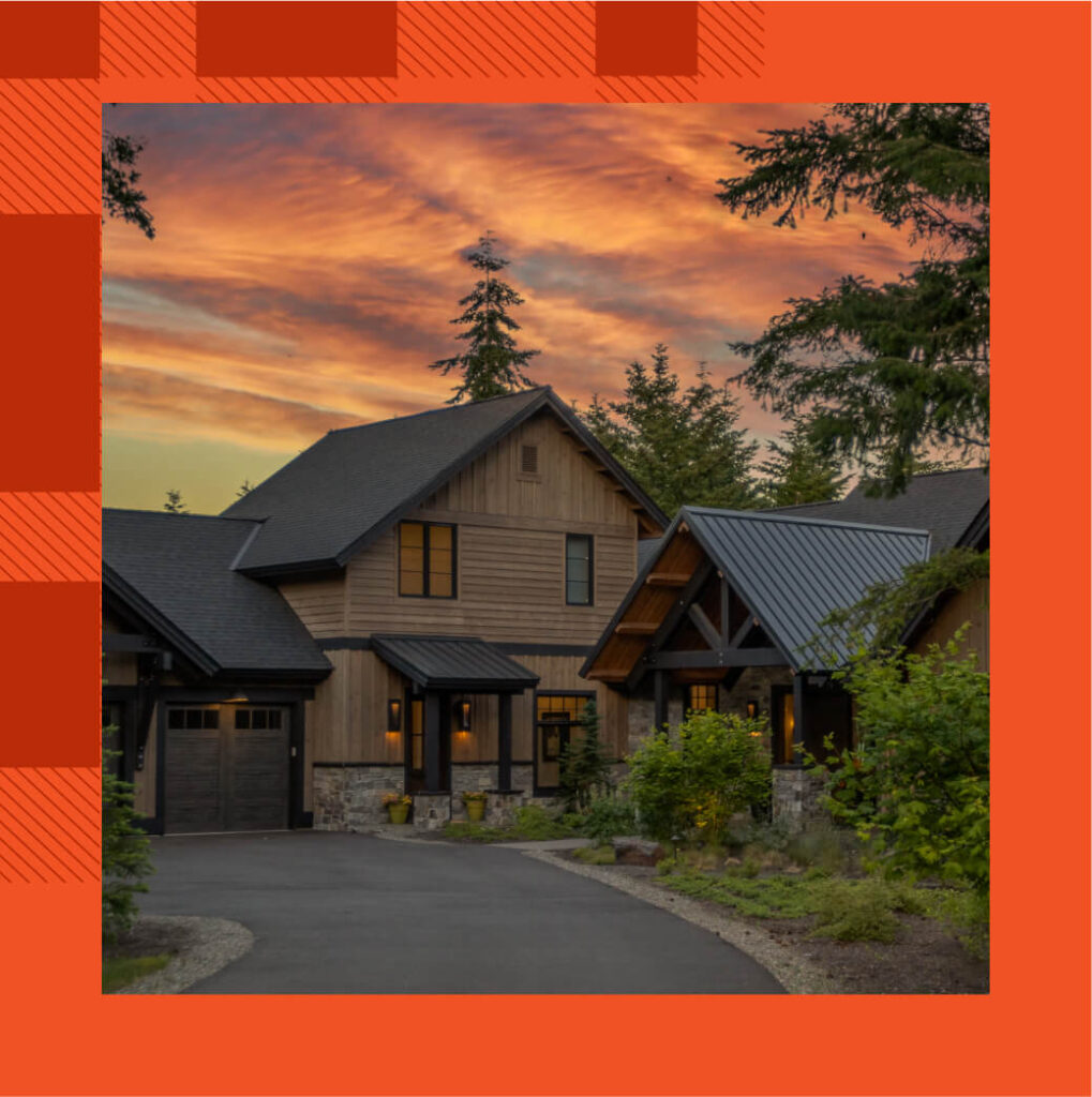 A modern house with a peaked roof, nestled amidst trees in the serene Suncadia Resort, basks under a vibrant orange and pink sunset sky.