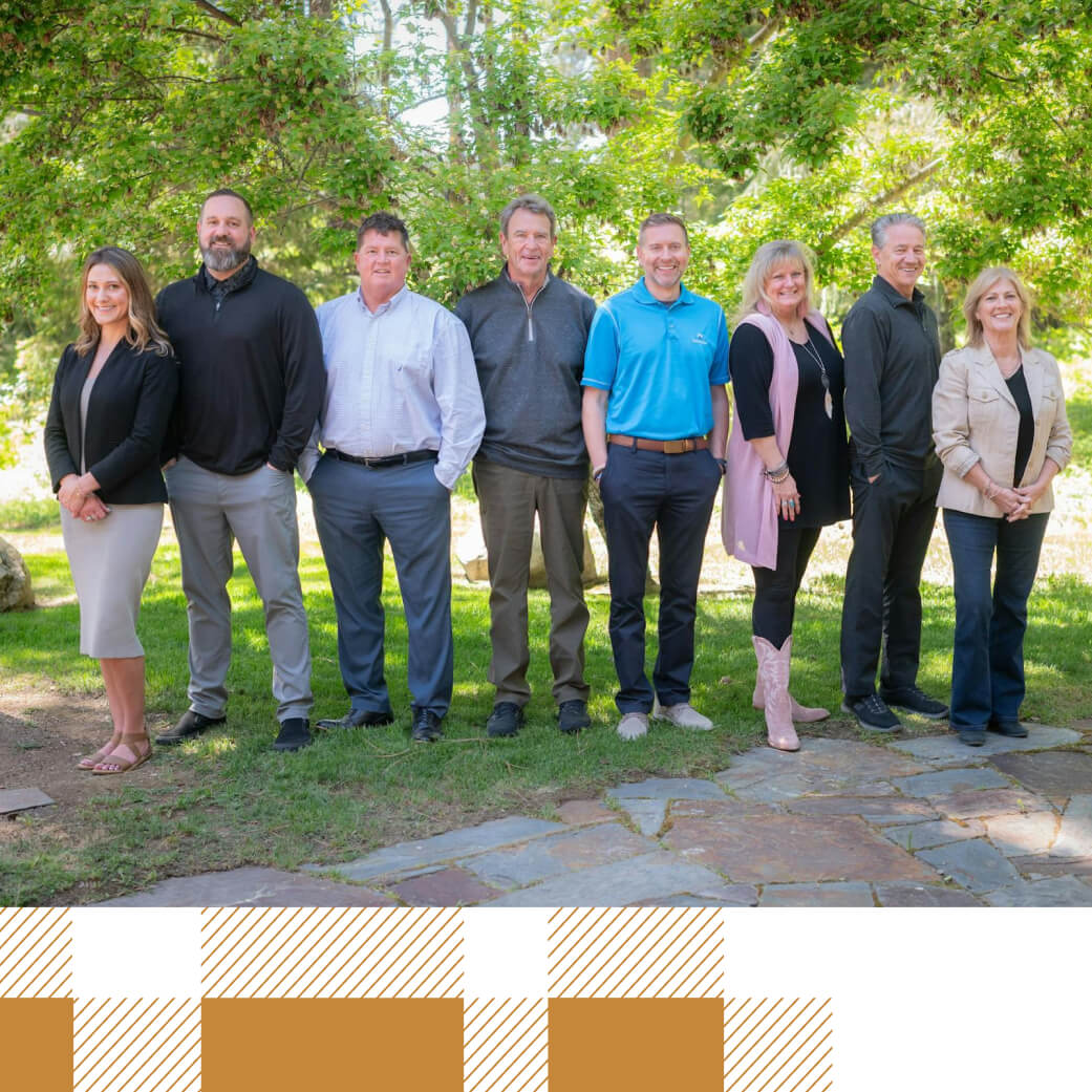 A group of eight people standing outdoors on a sunny day at Suncadia, Washington, with trees in the background and nearby Cle Elum restaurants offering a perfect spot for dining.