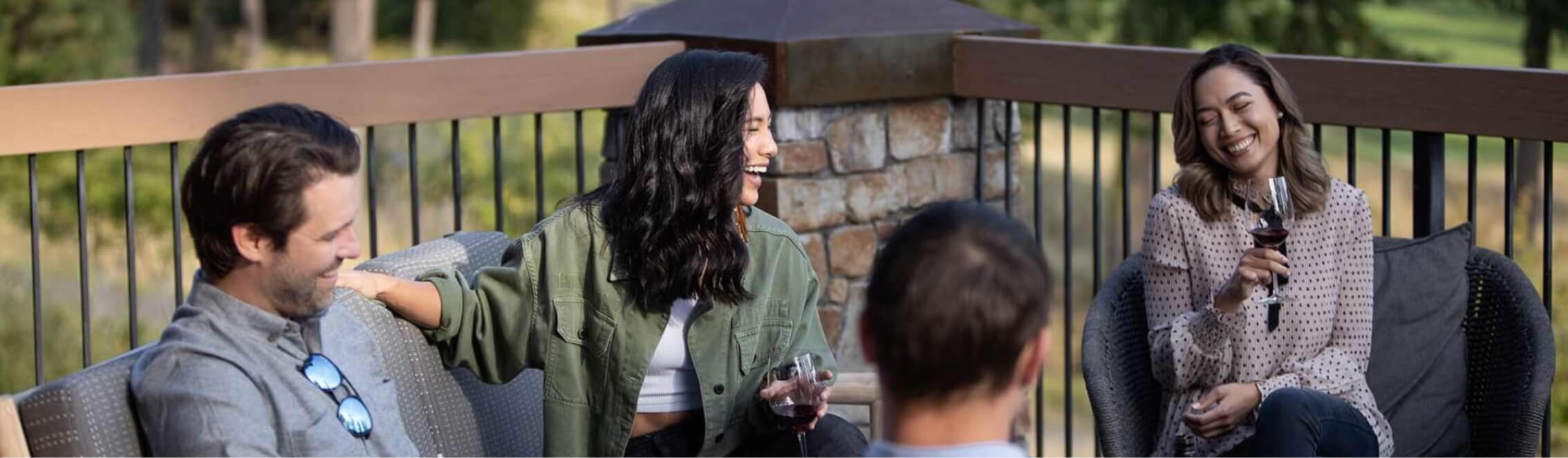 Four people sitting outdoors on a patio at Suncadia Resort, smiling and holding wine glasses.