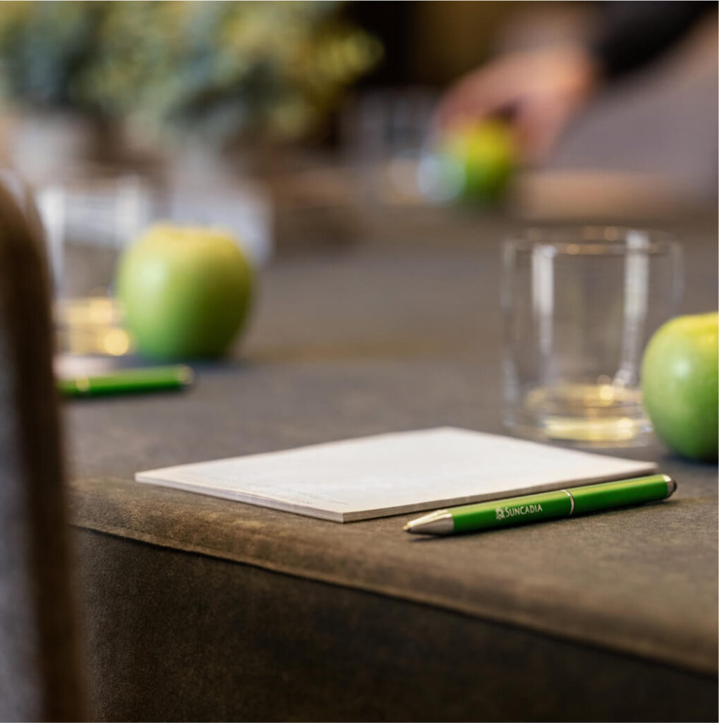 A table with notepads, green pens, apples, and glasses is set up for a meeting at Suncadia Resort in Washington.