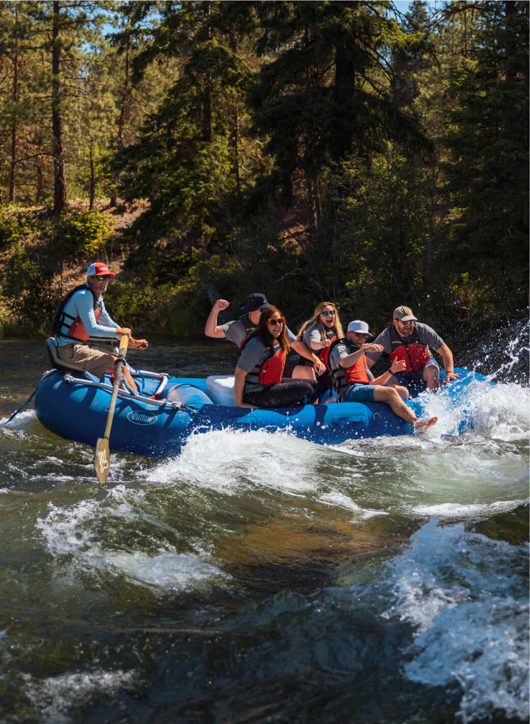 A group of people, wearing life jackets, are rafting on a river in a forested area near Suncadia Resort Washington, skillfully navigating through splashing water.