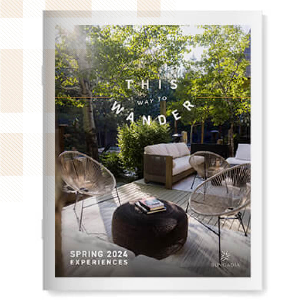 Outdoor patio at Suncadia Resort with modern chairs, a small table, and lush greenery. Text reads "This Way to Wander" and "Spring 2024 Experiences.