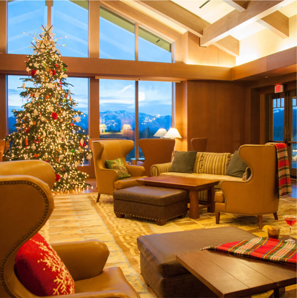 A cozy living room with plush brown chairs and a lit Christmas tree, offering a mountain view through large windows—true Suncadia charm for those dreaming of owning Suncadia real estate.