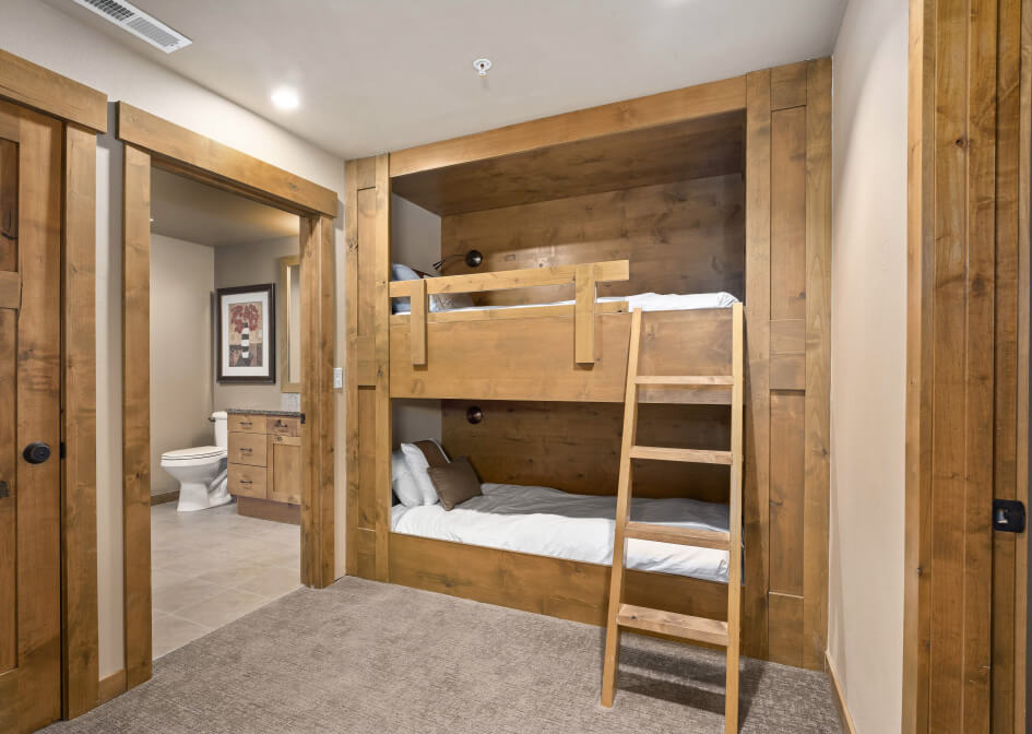 Cozy wooden bunk beds in a room with neutral tones, located near a bathroom, echo the warmth often found in Suncadia homes.