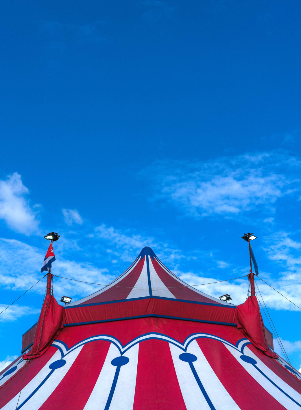 A red and white circus tent stands proudly under the clear blue sky, its vibrant colors echoing the charm of Suncadia Resort in Washington. A few scattered clouds drift by, adding to the picturesque setting reminiscent of those found near Suncadia homes.