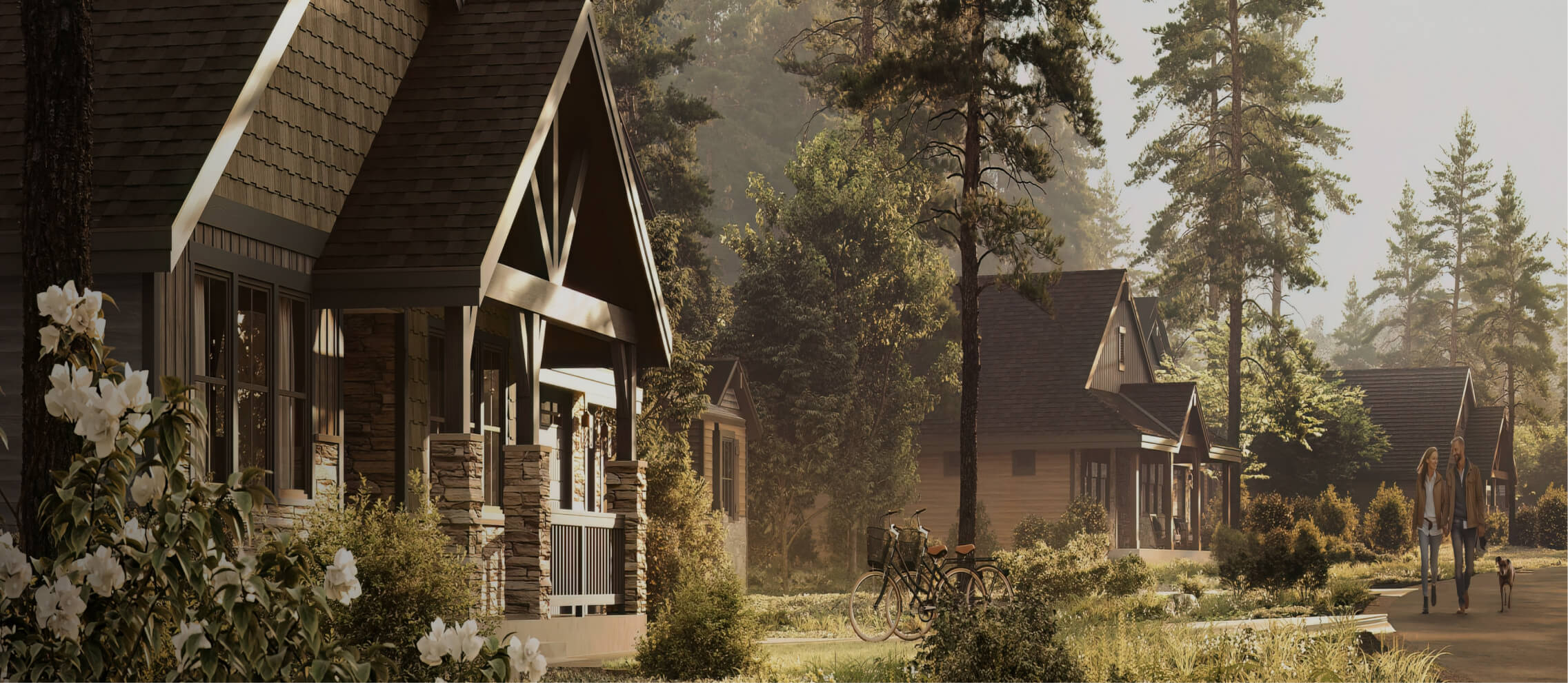 A peaceful suburban neighborhood with charming, cottage-style homes is reminiscent of Suncadia Resort, surrounded by lush trees and greenery. Two people stroll down the path, past parked bicycles.