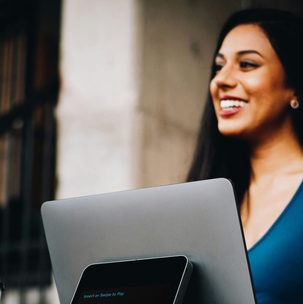 A woman smiling while working on a laptop outdoors, enjoying the serene backdrop of Suncadia real estate.