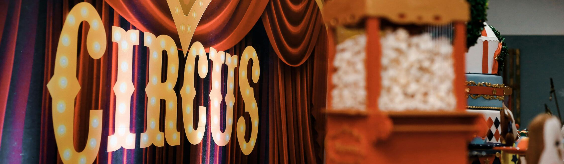 A large "Circus" sign with illuminated bulbs is displayed against a backdrop of red curtains, evoking the whimsical charm often found near Cle Elum restaurants. A popcorn machine sits invitingly in the foreground on the right, reminiscent of festive gatherings at Suncadia homes.