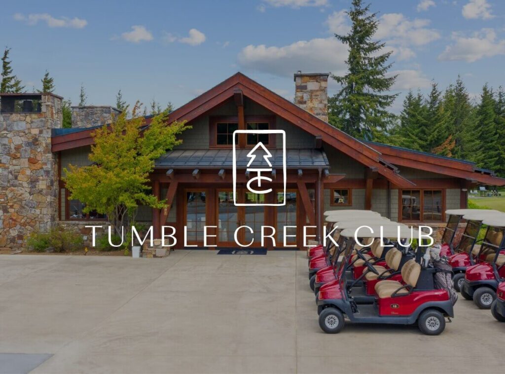 The entrance of Tumble Creek Club showcases a row of red golf carts parked in the foreground, with a charming wooden lodge-style building nestled in the backdrop, exemplifying the rustic elegance found throughout Suncadia Resort Washington.