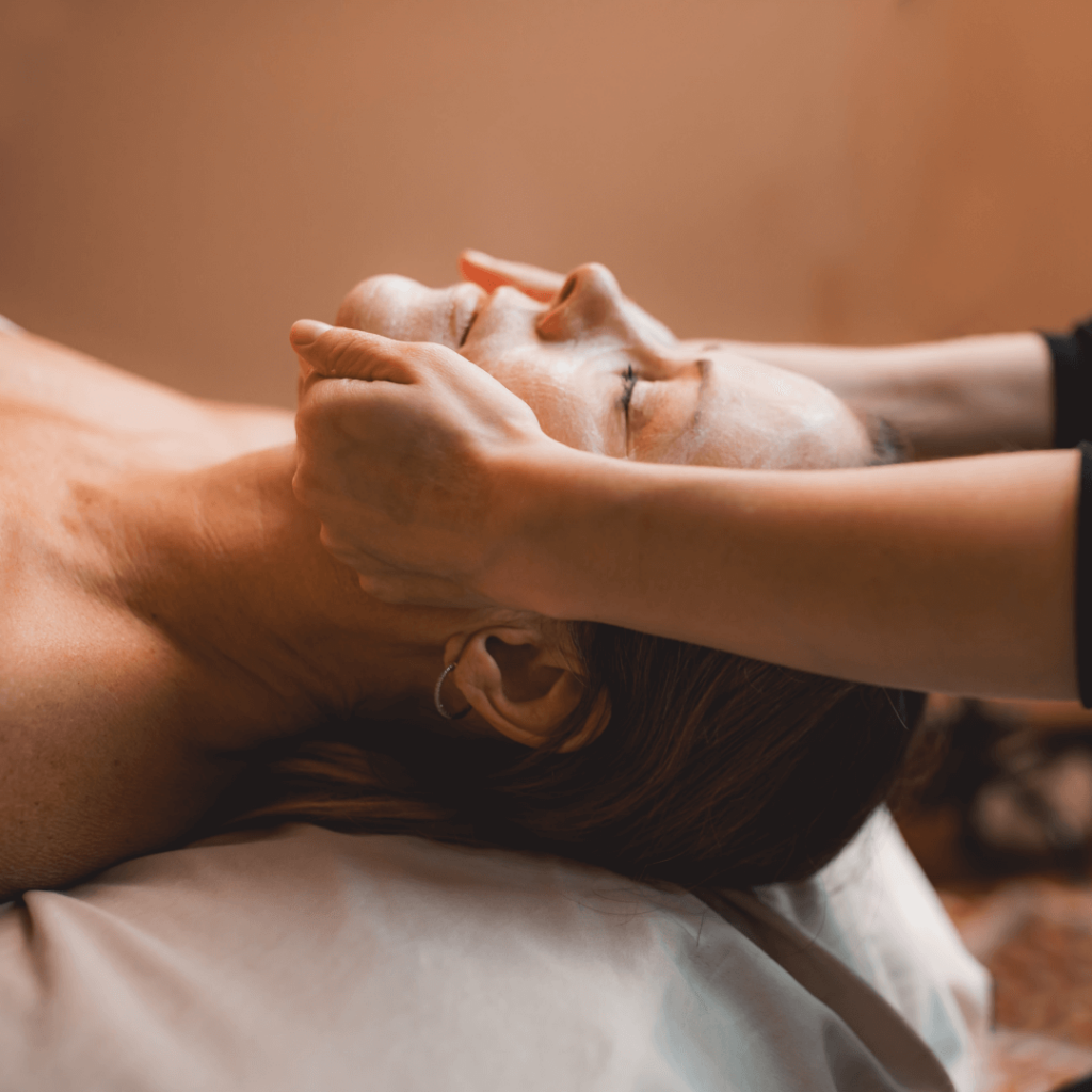 A person receives a facial massage while lying down.