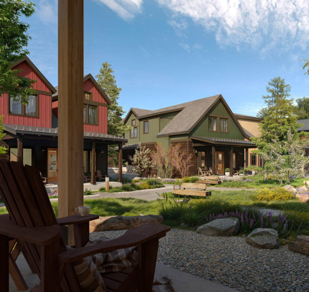 View from a porch chair overlooking a landscaped yard with gravel, plants, and several colorful, modern-style houses under a partly cloudy sky.