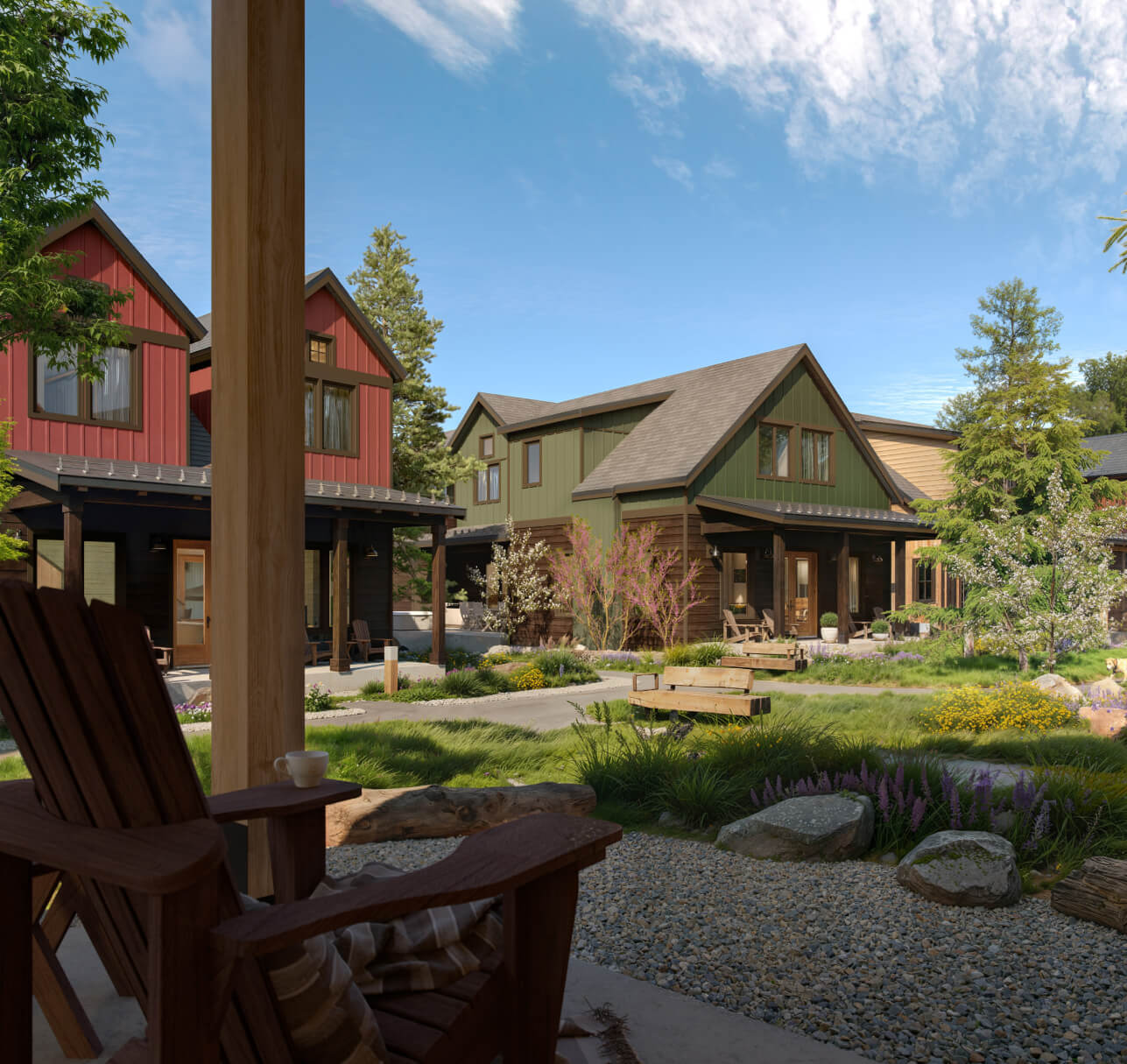 View from a porch chair overlooking a landscaped yard with gravel, plants, and several colorful, modern-style houses under a partly cloudy sky.