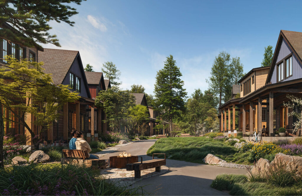 A landscaped path runs between modern wooden cabins, with people sitting by a fire pit and others relaxing on porches, surrounded by trees and greenery.