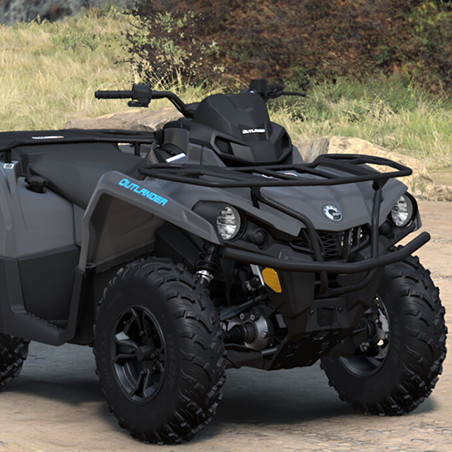 A black and gray Can-Am Outlander all-terrain vehicle is parked outdoors on a dirt path with grass and rocks in the background.