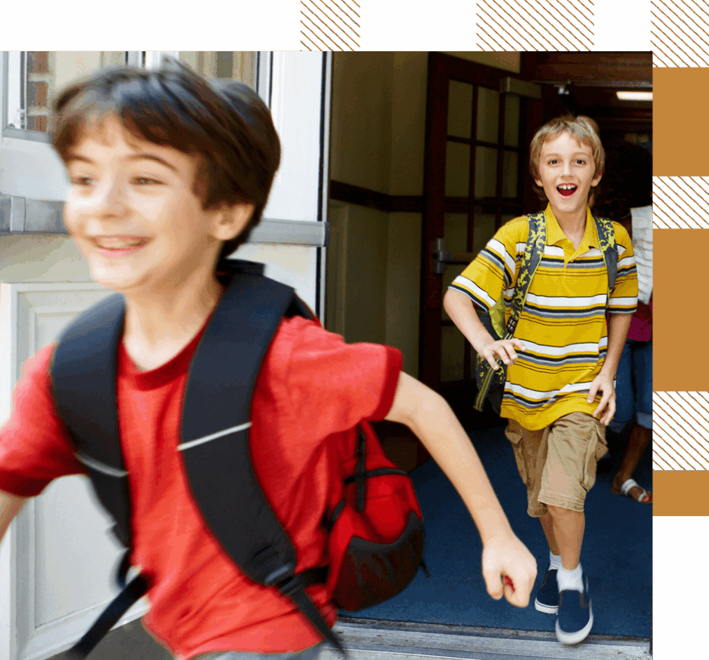 Two boys with backpacks running out of a school building, appearing excited and happy.