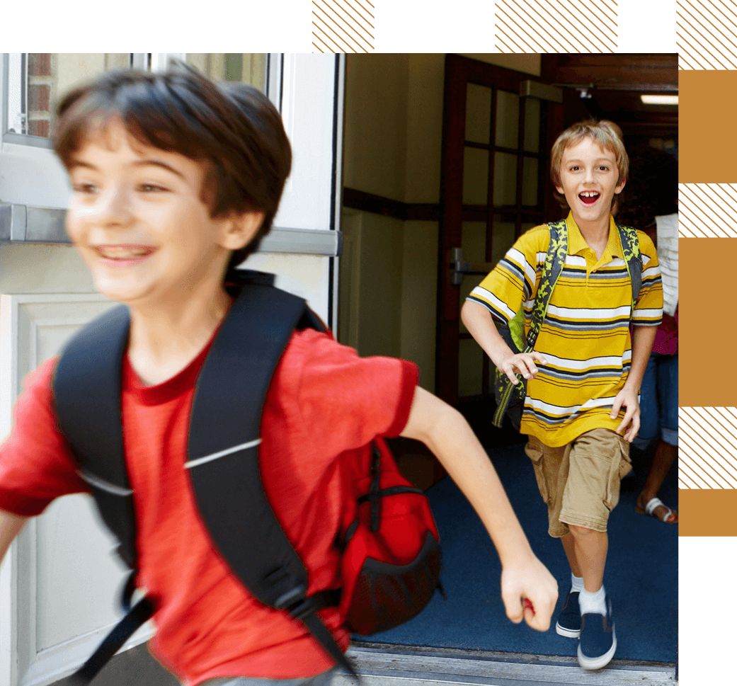 Two boys with backpacks running out of a school building, appearing excited and happy.