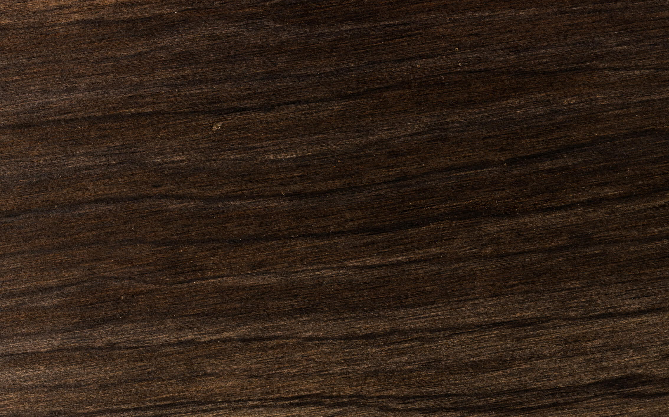 Close-up of a dark brown wooden surface showing natural grain patterns and subtle variations in color.