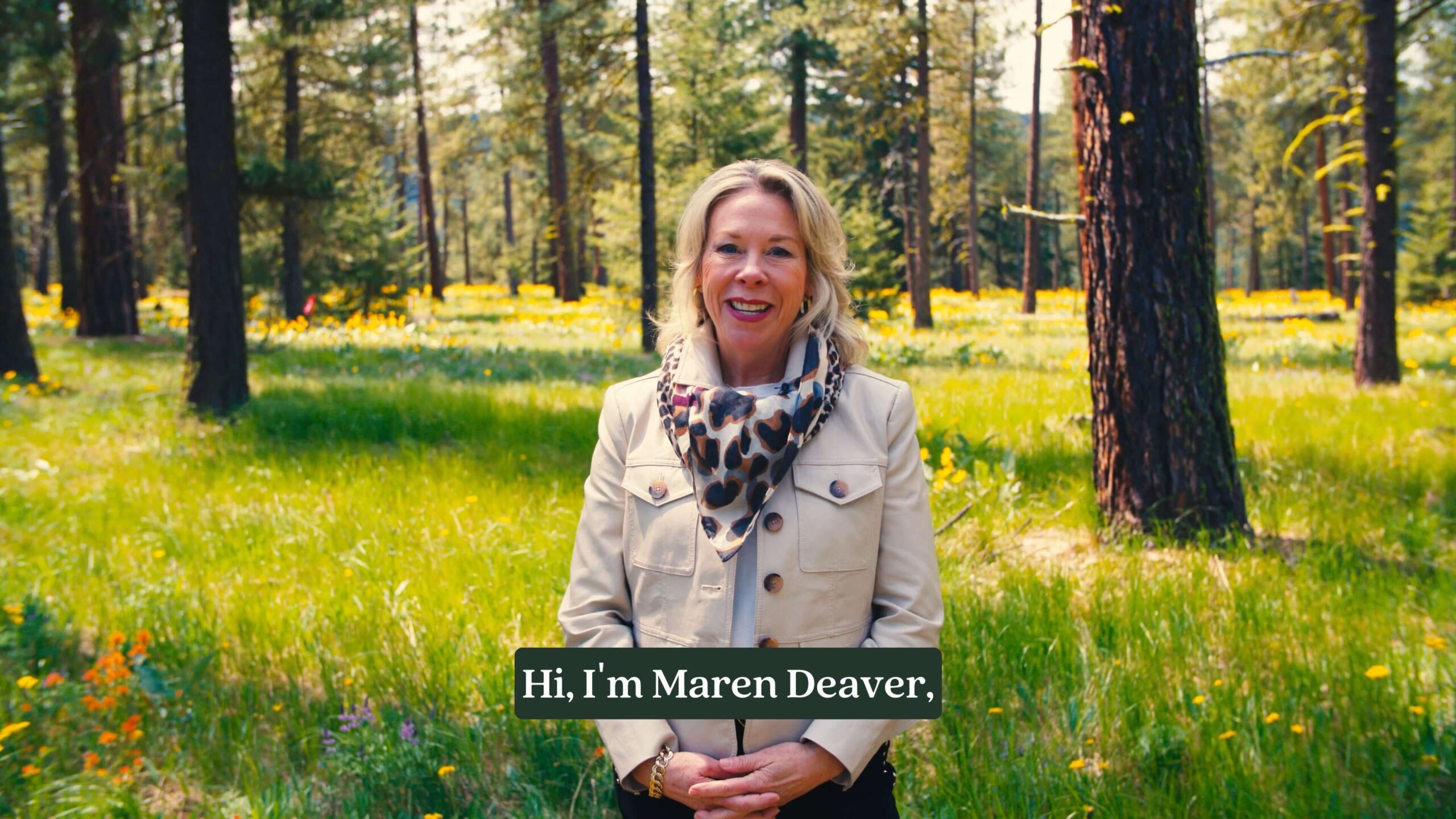 A woman stands in a sunlit forest clearing, wearing a beige jacket and scarf, with on-screen text that reads, "Hi, I'm Maren Deaver.