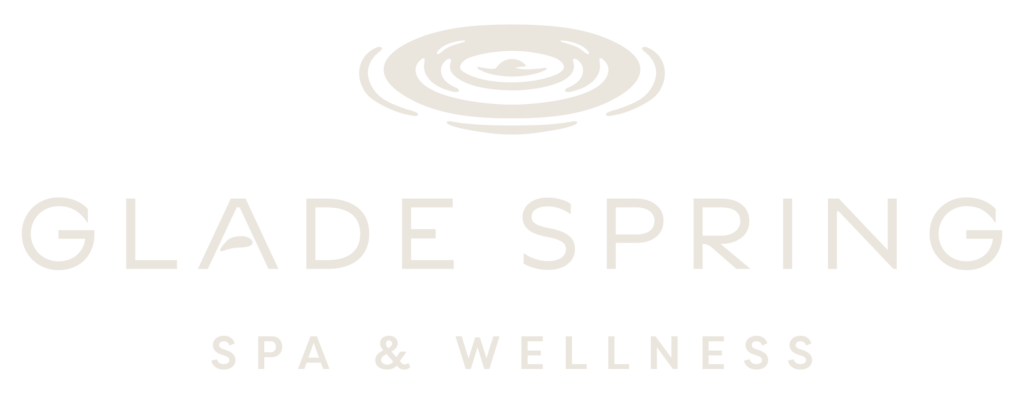 Minimalist logo with soft beige text reading Glade Spring Spa & Wellness below a simple ripple design, evoking calm and relaxation.