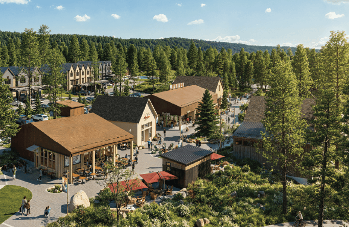 A lively outdoor shopping and dining area with rustic buildings, patio seating, and people walking among pine trees, set against a backdrop of forested hills under a blue sky.