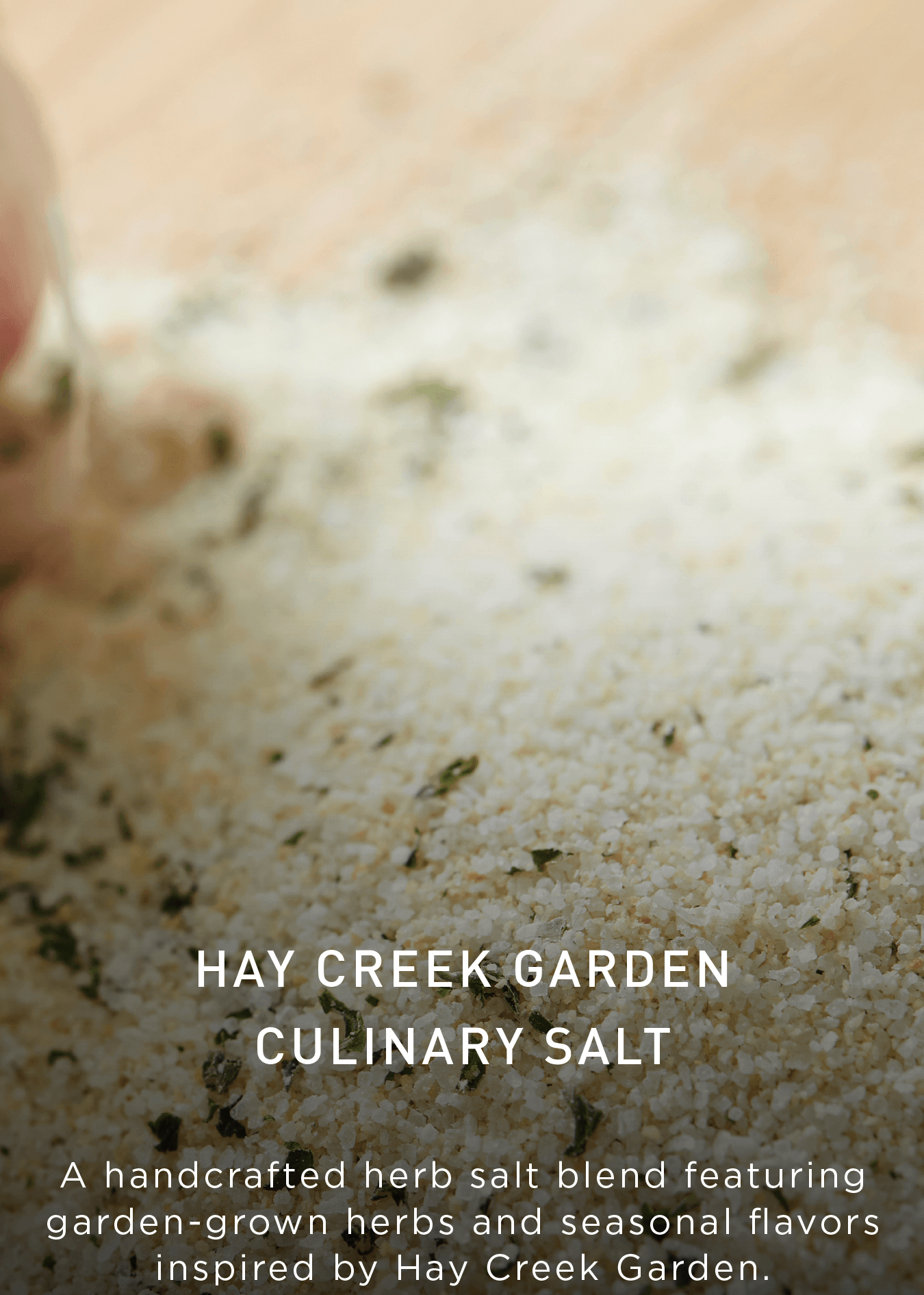 A close-up of a herb salt blend on a surface, featuring green herbs mixed with salt. Text reads: Hay Creek Garden Culinary Salt and describes it as a handcrafted blend with garden-grown herbs.